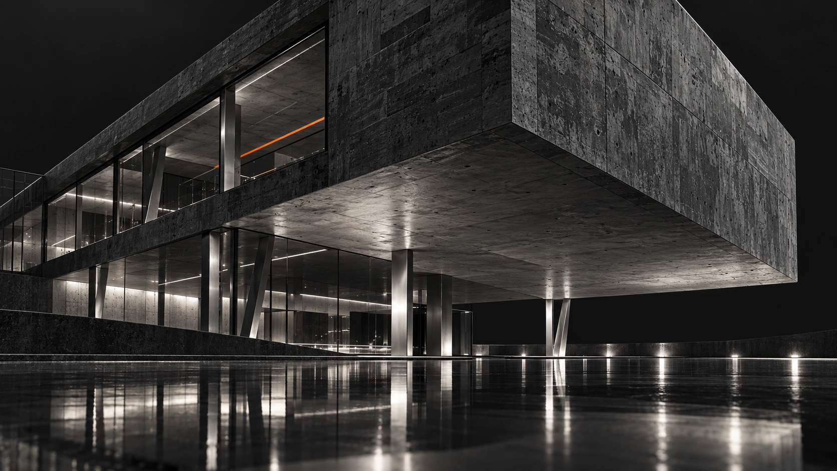A concrete cantilever above a lit glass pavilion at night